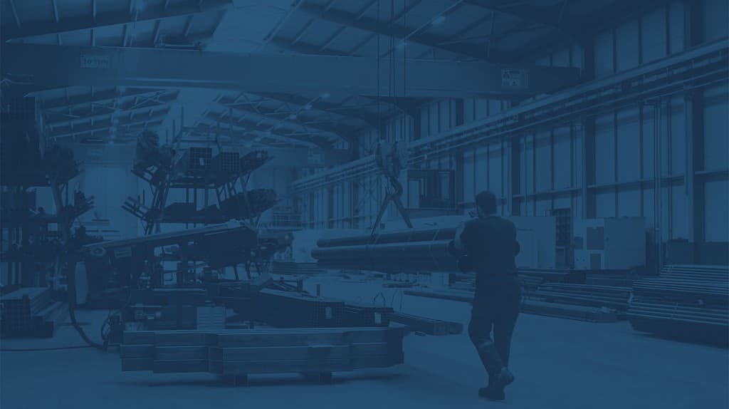Overhead crane and worker moving steel in a heavy manufacturing facility