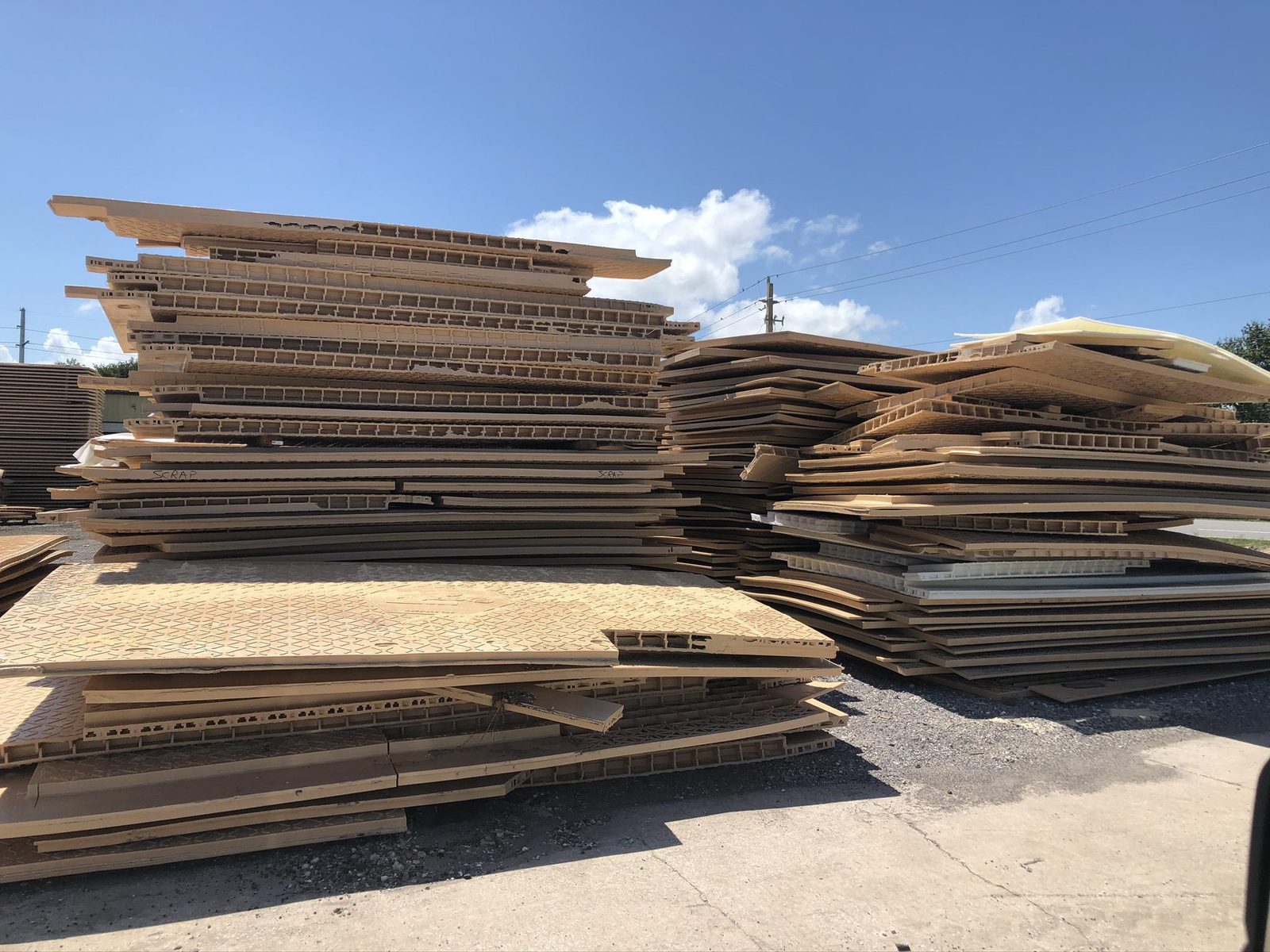 Stack of warped composite access mats in a manufacturing yard