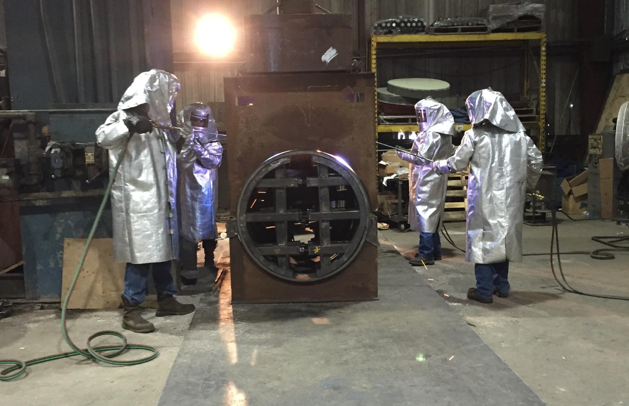 Crew in heat suits heating a large-diameter pipe extrusion on the original forming press