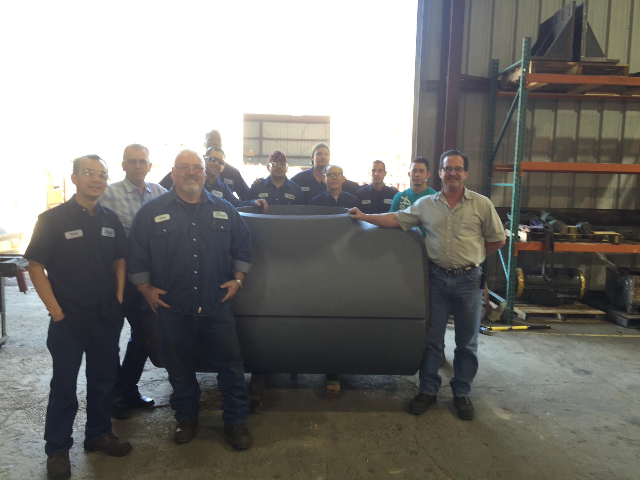 Manufacturing team standing with a large completed extrusion