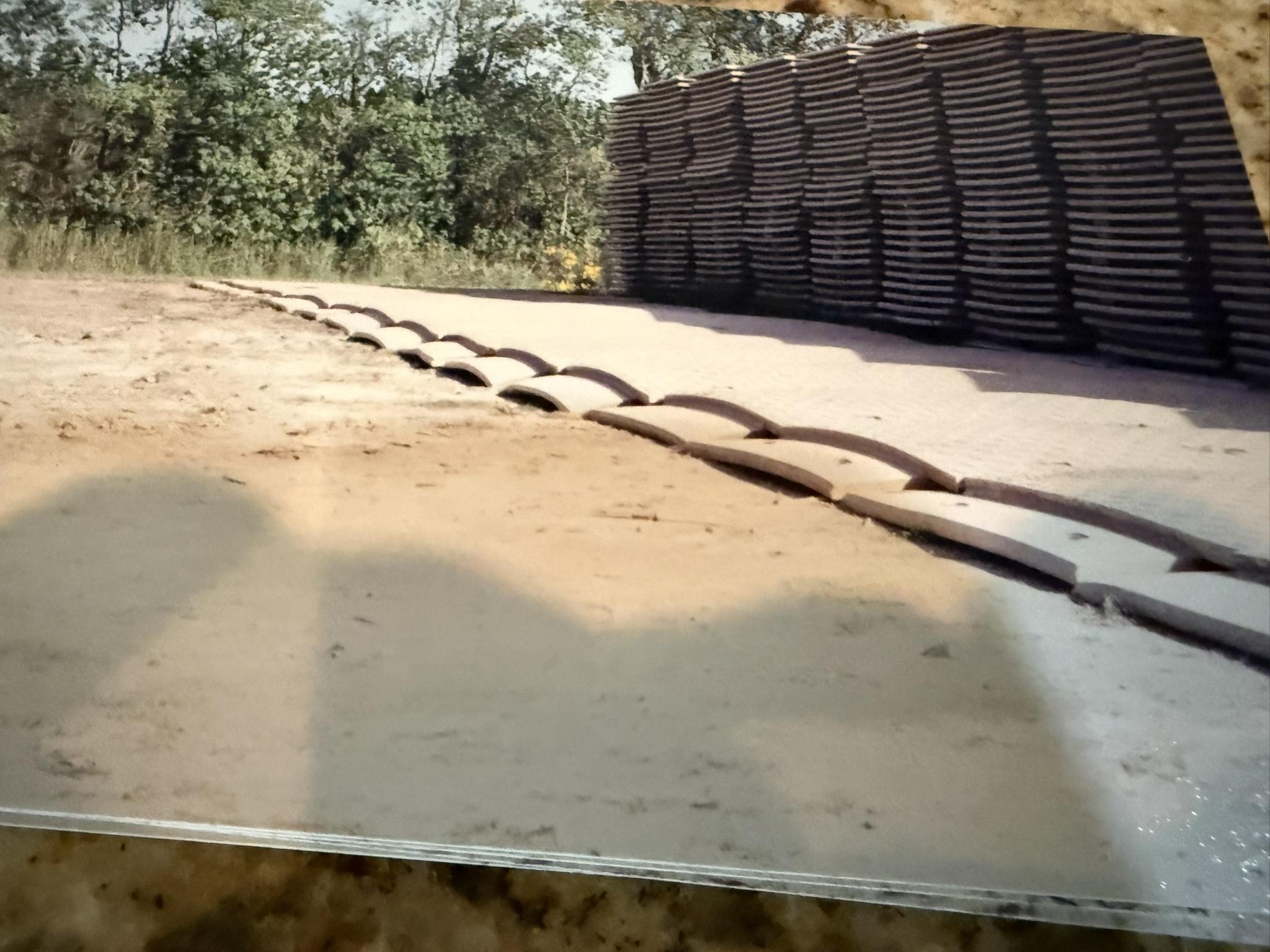 Installed composite mats arched into a repeating hump beside stacked mats