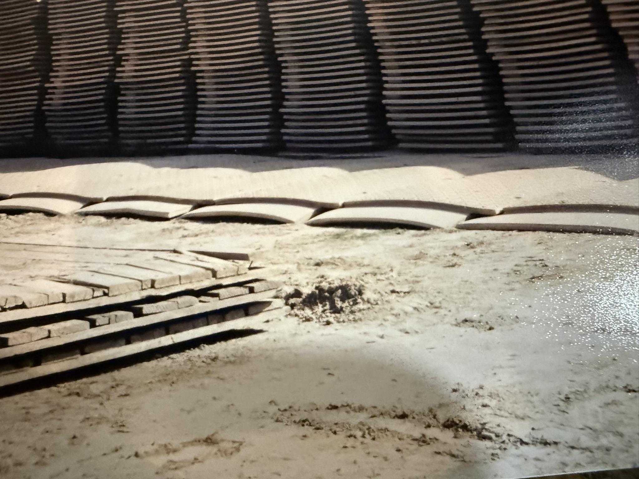 Close view of composite mats lifted into a repeating wave across a dirt pad